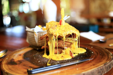 Closeup of Crispy Fried Chicken Lava Cheese on wooden board on wood table background in the restaurants. Foods concept. Warm lights tone.