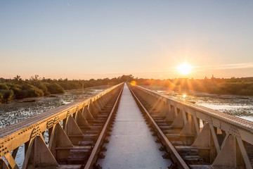 Old steel railway bridge on the river with beautiful sunset