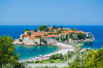 Fototapeta na wymiar Panoramic view of island of Sveti Stefan, on old stone houses with red tiled roofs on clear summer sunny day, Budva, Montenegro, Adriatic Sea, Balkans