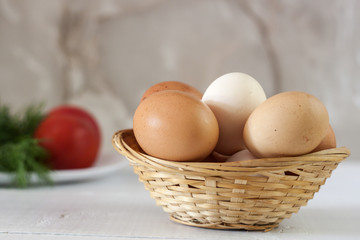 Raw eggs in a wicker basket on a white table