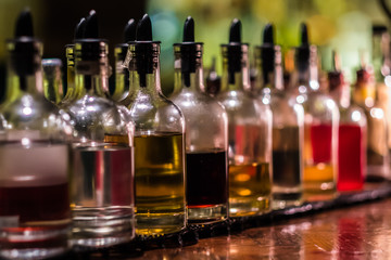 Bottles with syrups for mixing cocktails on bar counter. Alcohol drinks ingredients. Professional cocktail liquors. Horizontal image with selective focus. 