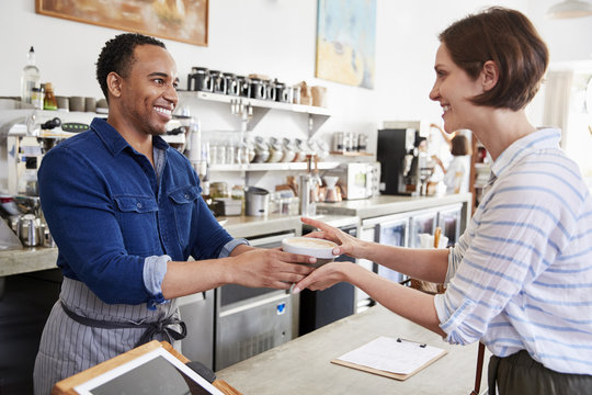 Male Barista Passing Coffee To A Female Coffee Shop Customer