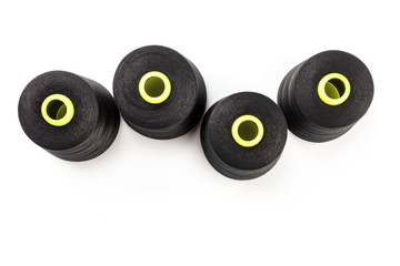 An overhead photo of large black thread spools, shot from above on a white background with copy space