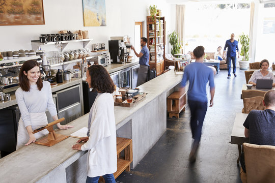 Customer At A Counter Of A Busy Coffee Shop, Elevated View