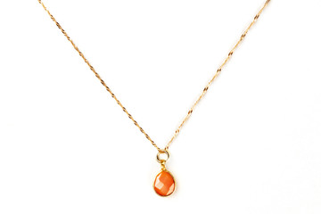 Overhead photo of an orange carnelian gemstone on a golden chain, on a white background with copy...