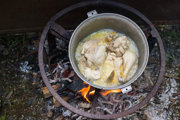 Cooking chicken in big kettle on open fire. Making kharcho or harcho soup. Traditional Georgian food.