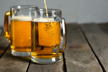 Pouring beer in glasses on rustic background
