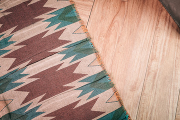 Laminate parquete floor. Light wooden texture. Thin aztec, mexican style print carpet. Minimalism interior design concept