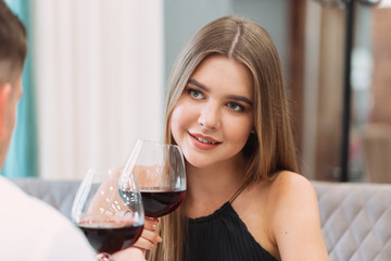 Beautiful young couple with glasses of red wine in luxury restaurant