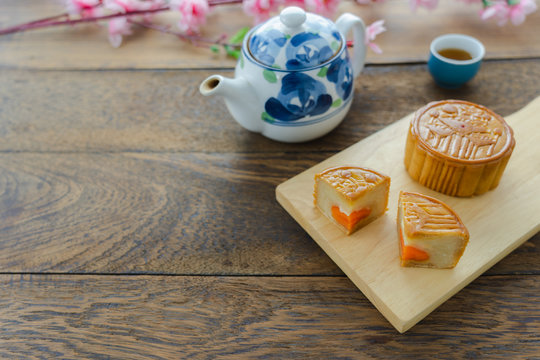 Close up image of food dessert decorations Chinese Moon Festival background concept.Food & drink the cake with tea cup and pink blossom on modern rustic wooden plank.Free space for design add text.