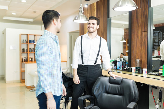 Barber Offering Seat To Customer In Salon
