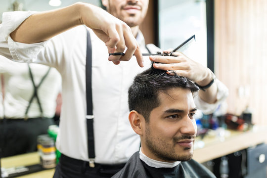 Professional Barber Giving Haircut To Male In Shop
