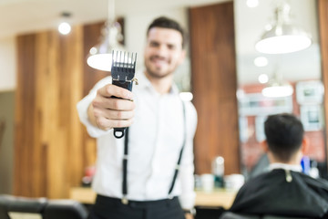 Hairstylist Holding Trimmer With Focus On Hand In Salon