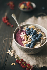 Delicious smoothie bowl with blueberries, rolled oats and chia seeds on the wooden background