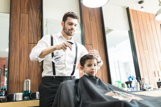 Hairdresser Sprinkles Water On Customer's Hair In Barber Shop