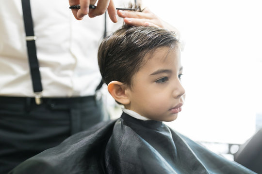 Little Client Is Getting Haircut By Hairdresser At Barber Shop