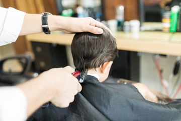 Barber Giving Haircut To Client Using Trimmer In Shop