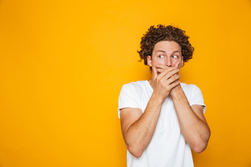 Portrait of a shocked curly haired man covering mouth