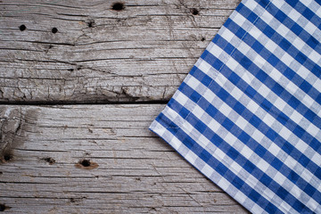 Blue checkered tablecloth on wooden rustic table background. Copy space, top view