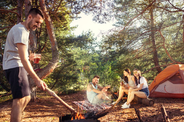 Party, camping of men and women group at forest. They relaxing against green grass. The vacation, summer, adventure, lifestyle, picnic concept
