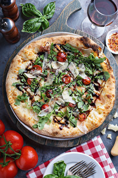Pizza with arugula, tomato and parmesan