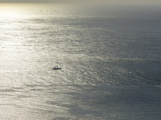 High key shot into early morning sunlight of a yacht sailing on a silver sea, Devon, UK