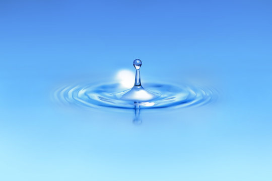 Closeup on drop of water falling in a blue liquid.