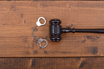  Judge Gavel and Handcuffs on a black wooden background.
