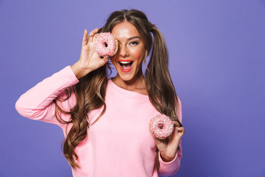 Portrait of a cute girl in sweatshirt posing with donuts