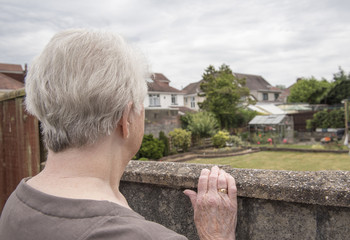 Senior woman spying over her neighbours wall 
