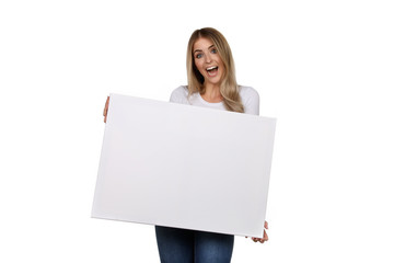 Hübsche blonde Frau schaut begeistert und hält eine leere Leinwand in ihren Händen