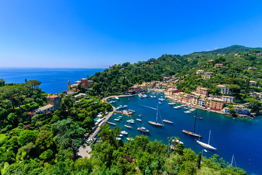 Portofino, Italy - colorful houses and yacht in little bay harbor. Liguria, Genoa province, Italy. Italian fishing village with beautiful sea coast landscape in summer season.