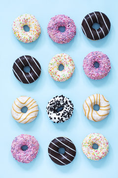 Sweet and colourful donuts glazed with sprinkles and chocolate. Set of different type of donuts on the blue background.
