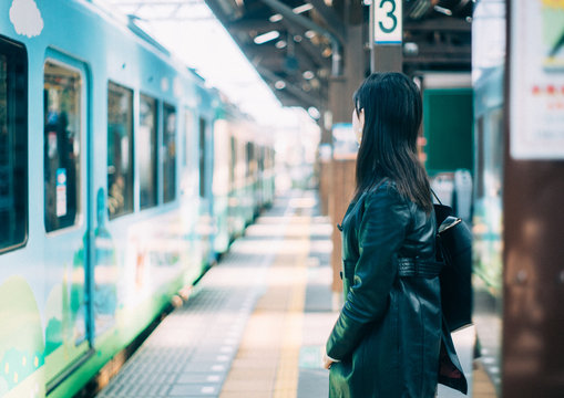 駅のホームで電車を待つ女性