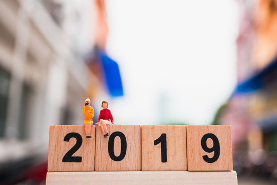 Miniature people, couple woman sitting on wooden block 2019 using as business and social concept - Powered by Adobe