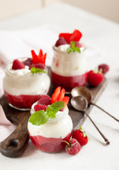 Jars of natural white yogurt with berry sauce decorated with fresh strawbeery, raspberry and mint