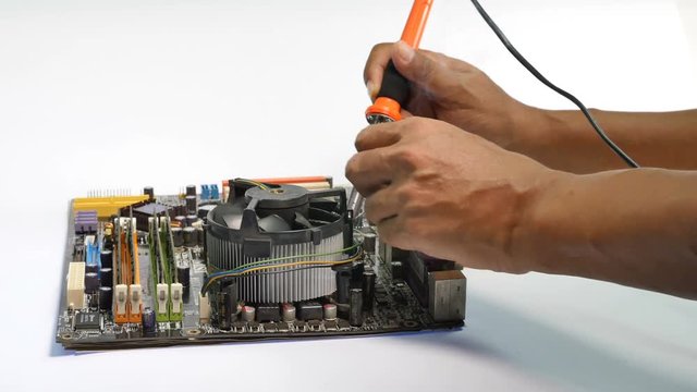 A soldering iron is composed of a heated metal tip and an insulated handle..computer mainboard on wooden table on black background