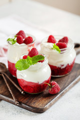 Jars of natural white yogurt with berry sauce decorated with fresh raspberry and mint