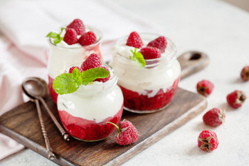 Jars of natural white yogurt with berry sauce decorated with fresh raspberry and mint