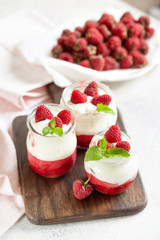 Jars of natural white yogurt with berry sauce decorated with fresh raspberry and mint