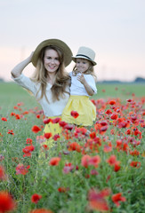 Cute little girl with her mother walking in the field with poppies flowers family look sunset summer 