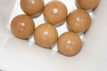 Seven round wooden balls in a white square box