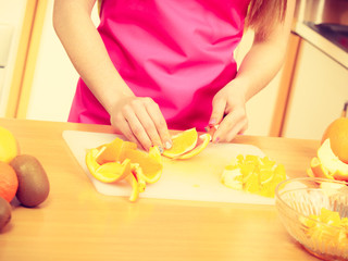 Obraz na płótnie Canvas Woman housewife in kitchen cutting orange fruits