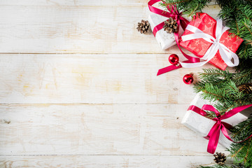 Christmas decoration composition. Christmas gift boxes, pine tree branches, red balls, candy canes, on light grey background. Flat lay, top view.