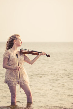 Woman playing violin on violin near beach