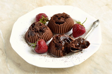 Delicious chocolate souffle with prunes and strawberries sprinkled with cocoa