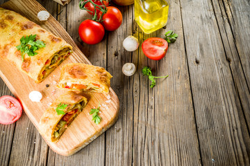 Vegetable savory strudel, homemade autumn baking, with tomatoes, bell pepper, mushrooms, wooden background copy space