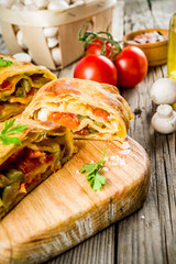 Vegetable savory strudel, homemade autumn baking, with tomatoes, bell pepper, mushrooms, wooden background copy space