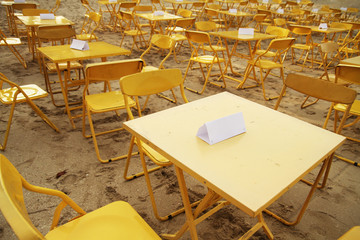 Reserved yellow steel tables on the beach