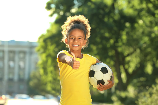 Cute African American girl with soccer ball in park